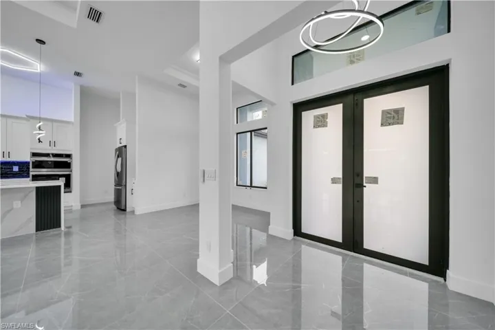 Entryway with a high ceiling, light marble finish flooring, a chandelier, recessed lighting, and french doors