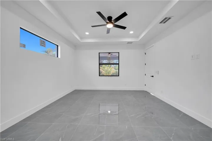 Empty room with a raised ceiling, a ceiling fan, and recessed lighting