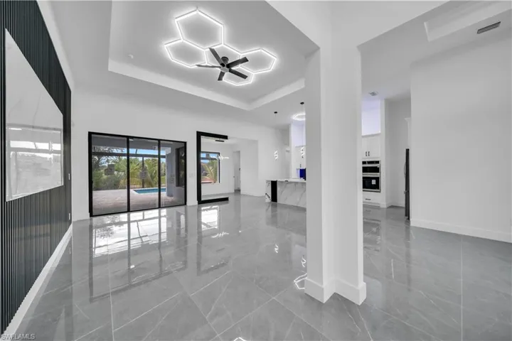 Unfurnished room featuring a tray ceiling, marble tiled flooring, and ceiling fan