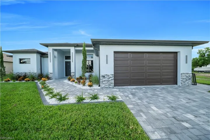 View of front of property featuring stone siding, stucco siding, a front lawn, and a garage