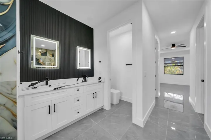 Full bath featuring double vanity, ceiling fan, recessed lighting, and marble look tile flooring