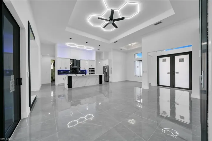 Unfurnished living room featuring a tray ceiling and ceiling fan