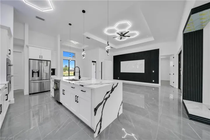 Kitchen with open floor plan, light marble finish flooring, stainless steel appliances, and a tray ceiling