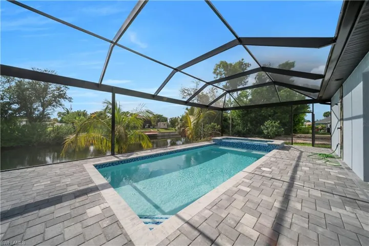 View of swimming pool with a pool with connected hot tub, a patio area, a water view, and a lanai