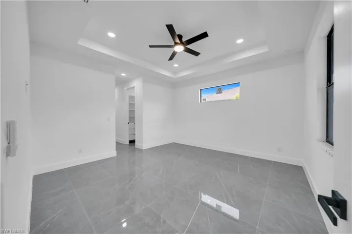 Spare room with a raised ceiling, recessed lighting, ceiling fan, and marble finish floors