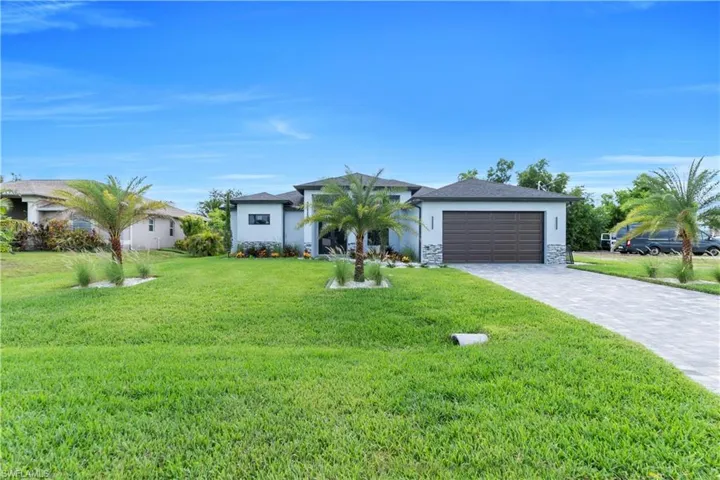 Single story home with an attached garage, stucco siding, decorative driveway, and a front lawn