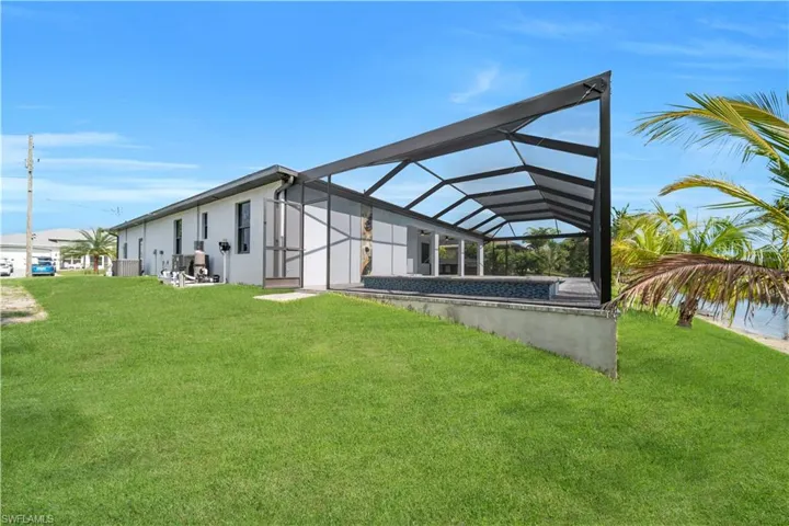 Back of property featuring a lawn, stucco siding, and a lanai