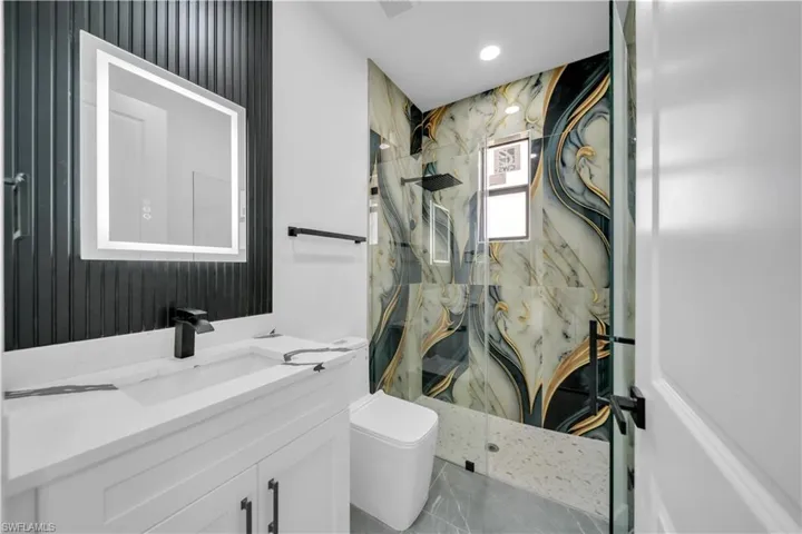 Bathroom with a marble finish shower, vanity, and recessed lighting