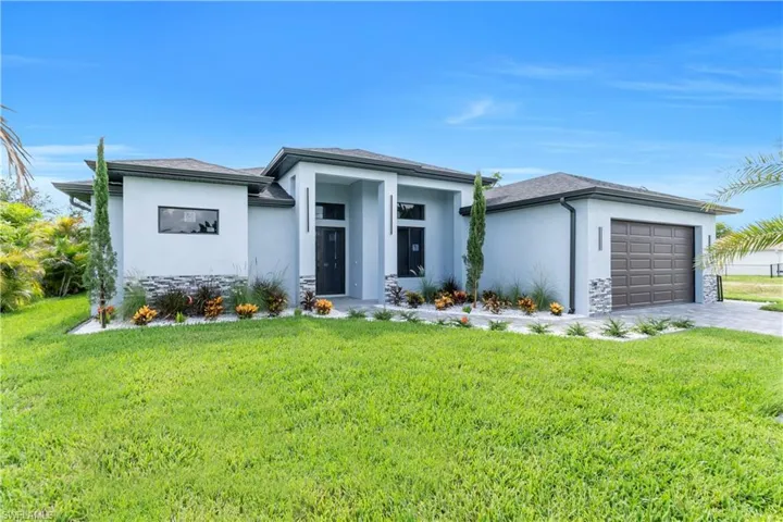 Prairie-style home with stucco siding, an attached garage, a front lawn, and stone siding
