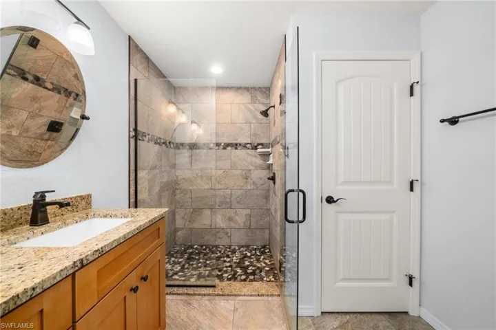 Bathroom featuring vanity, a shower stall, light tile patterned flooring, and recessed lighting