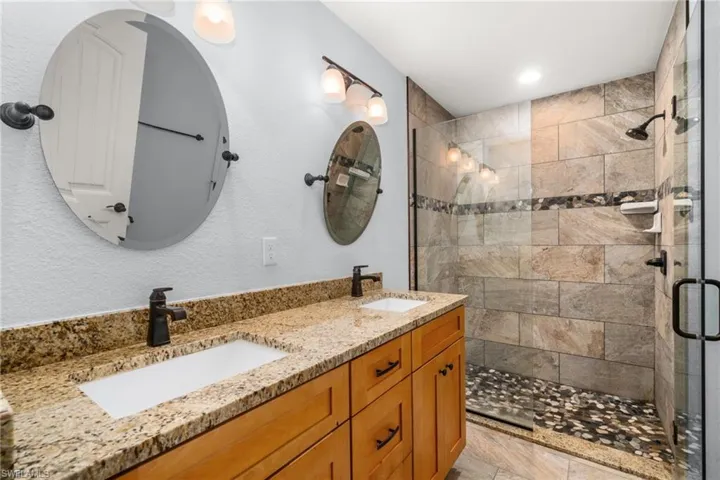 Bathroom featuring a stall shower, double vanity, and a textured wall