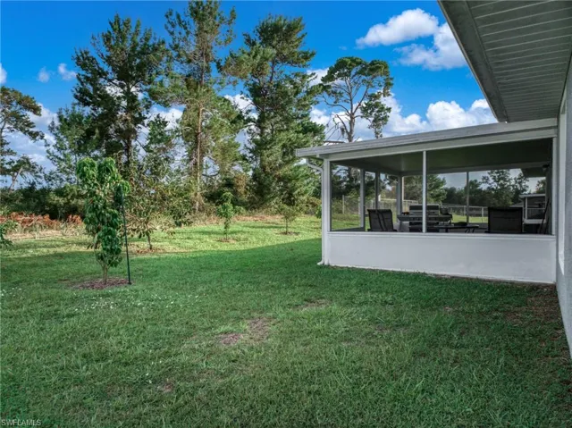 View of grassy yard with a sunroom