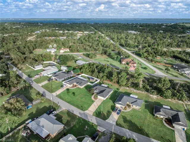 Aerial view of property and surrounding area featuring nearby suburban area and a large body of water