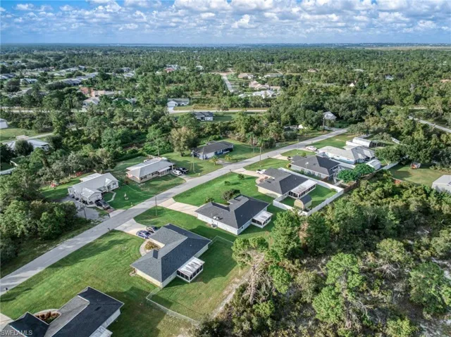 Aerial view of property's location featuring nearby suburban area and a forest
