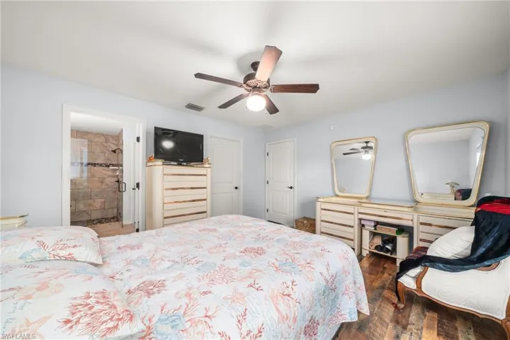 Bedroom featuring dark wood-style floors, connected bathroom, and ceiling fan