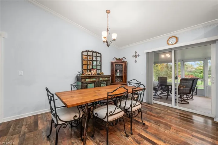 Dining area featuring ornamental molding, dark wood-style flooring, a chandelier, and vaulted ceiling