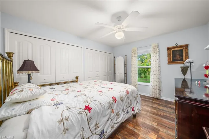 Bedroom with dark wood-style floors, two closets, and a ceiling fan