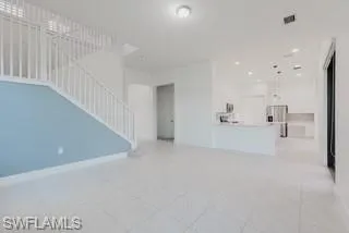 Unfurnished living room featuring stairs and light tile patterned floors