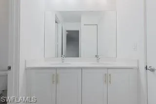 Full bathroom featuring double vanity and toilet