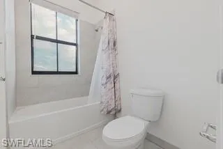 Bathroom with shower / bath combo with shower curtain and tile patterned flooring