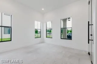 Empty room featuring light carpet, healthy amount of natural light, and recessed lighting
