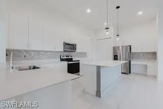 Kitchen with a breakfast bar, white cabinets, hanging light fixtures, appliances with stainless steel finishes, and recessed lighting