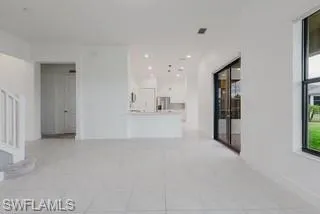 Unfurnished living room featuring light tile patterned floors and stairs