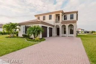 Mediterranean / spanish-style home featuring a front yard, a tile roof, decorative driveway, and stucco siding