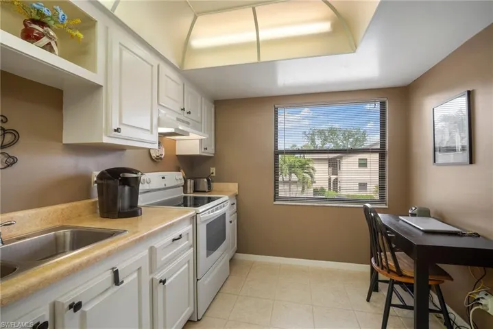 Kitchen with sink, white cabinets, electric stove, and light tile patterned floors