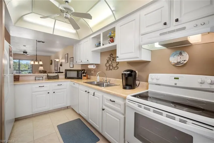 Kitchen featuring sink, decorative light fixtures, white cabinetry, white appliances, and kitchen peninsula