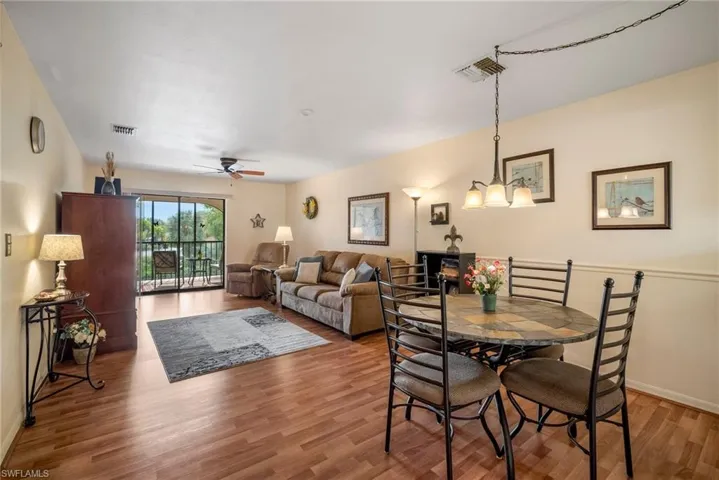 Dining room with hardwood / wood-style floors and ceiling fan with notable chandelier