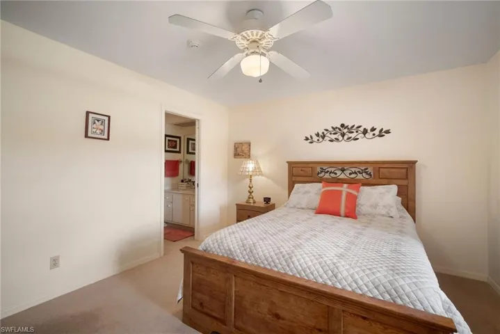 Bedroom with ceiling fan, ensuite bath, and light carpet