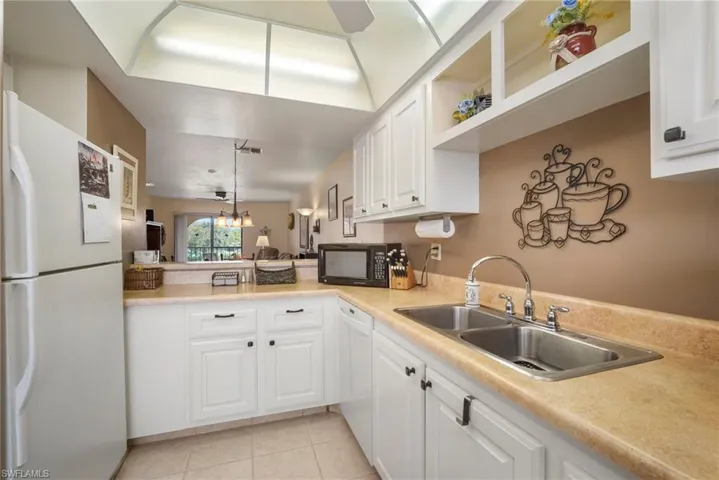 Kitchen with sink, white appliances, white cabinetry, and ceiling fan