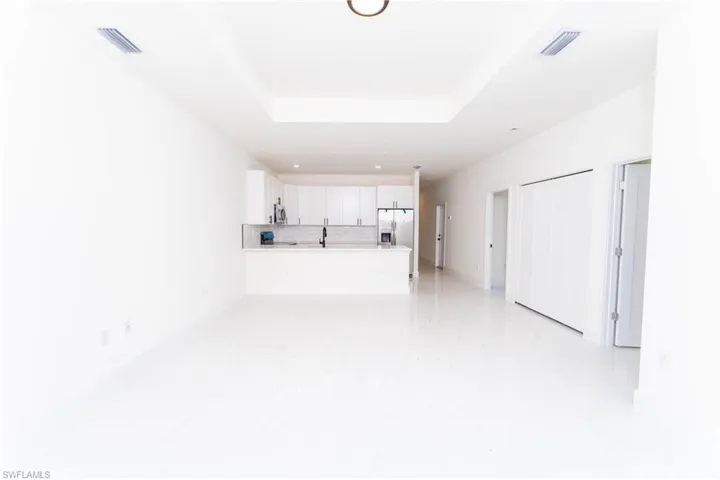 Unfurnished living room featuring a tray ceiling and recessed lighting