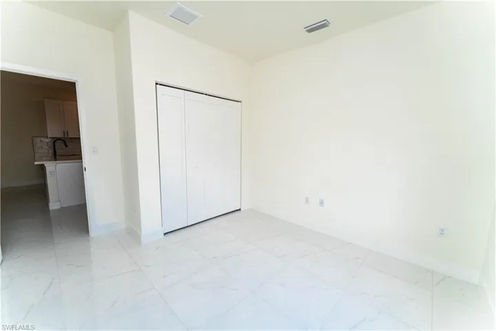 Unfurnished bedroom with light marble finish floors and a closet
