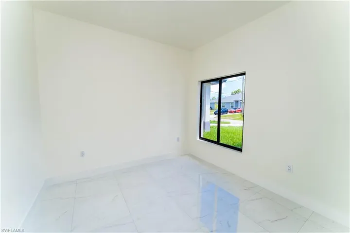 Spare room featuring light marble finish floors and baseboards