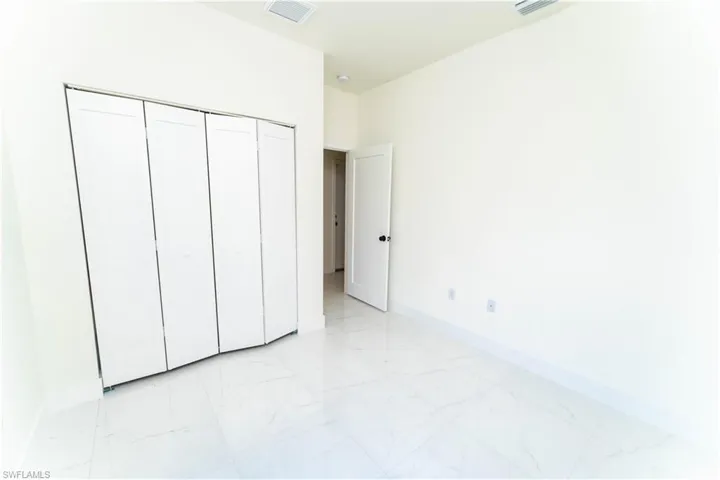 Unfurnished bedroom featuring a closet and light marble finish floors