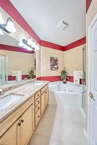 Bathroom with tile patterned flooring, vanity, and plus walk in shower