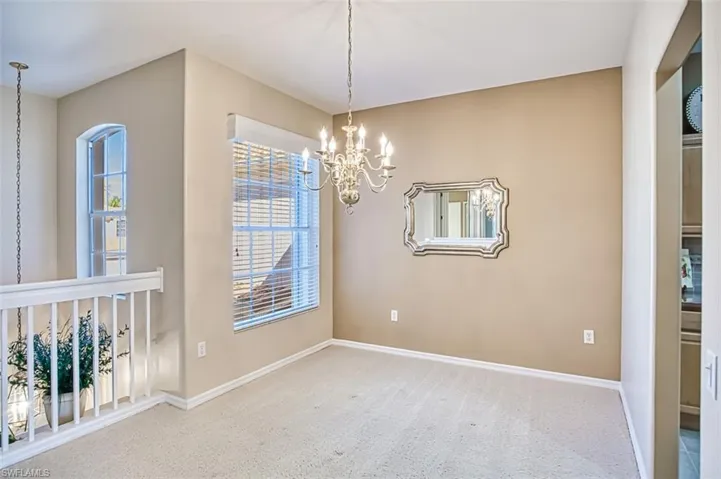 Carpeted empty room with an inviting chandelier