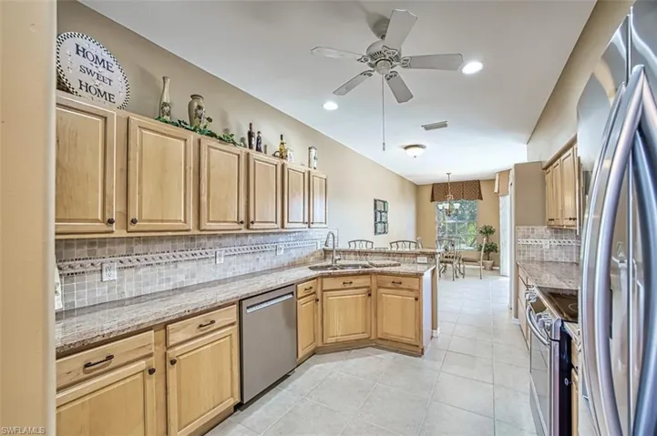 Kitchen featuring light stone countertops, sink, stainless steel appliances, backsplash, and pendant lighting