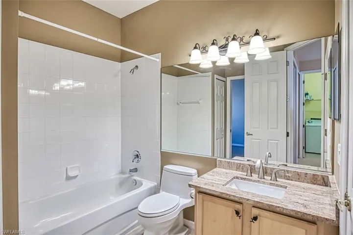 Full bathroom featuring tiled shower / bath combo, toilet, washer / clothes dryer, and vanity