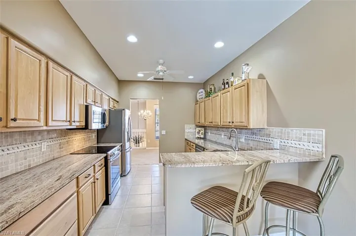 Kitchen featuring a kitchen breakfast bar, kitchen peninsula, stainless steel appliances, and light brown cabinetry