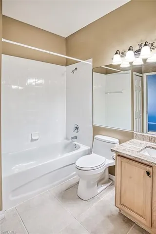 Full bathroom featuring toilet, tile patterned floors, vanity, and tiled shower / bath combo
