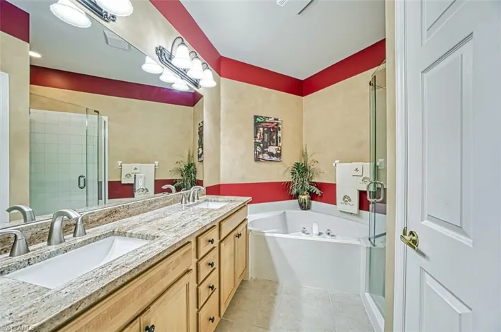 Bathroom featuring tile patterned flooring, vanity, and separate shower and tub