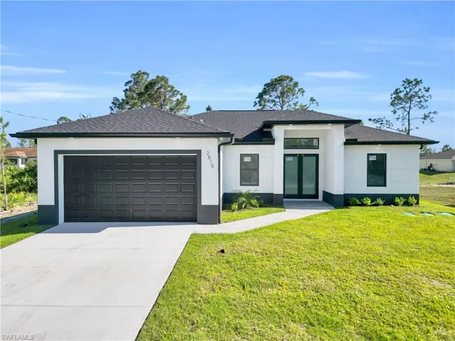 Prairie-style home featuring stucco siding, an attached garage, french doors, concrete driveway, and a front yard