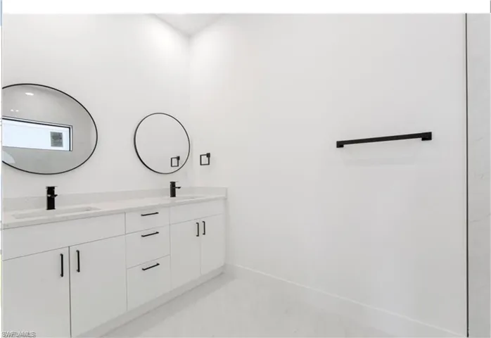 Full bathroom with double vanity and baseboards