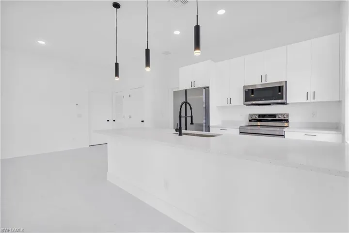Kitchen featuring stainless steel appliances, a sink, white cabinets, recessed lighting, and pendant lighting