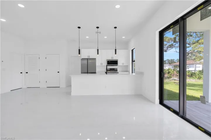 Kitchen featuring appliances with stainless steel finishes, recessed lighting, white cabinets, a peninsula, and decorative light fixtures