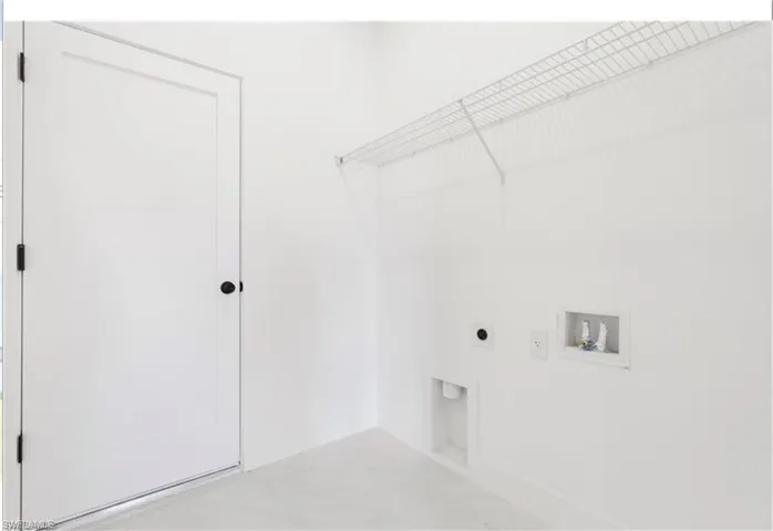 Washroom with hookup for an electric dryer, hookup for a washing machine, and baseboards