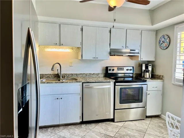 Kitchen with cream cabinets, dark stone counters, sink, appliances with stainless steel finishes, and ceiling fan